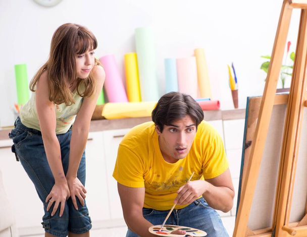 Νεαρό ζευγάρι απολαμβάνει ζωγραφική στο σπίτι - Φωτογραφία, εικόνα