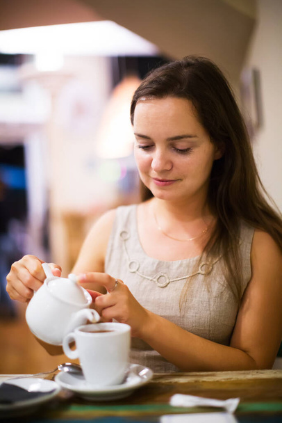 Cheerful young girl rests in cafe behind cup of tea - Foto, afbeelding