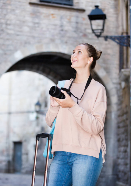 Young girl holding camera in hands and photographing at a city  - Photo, Image