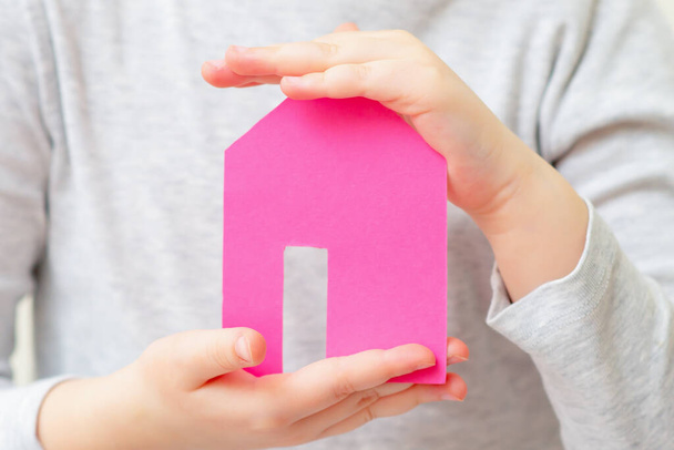 Paper house in hands of child dreaming of home. Family and home concept. - Photo, Image