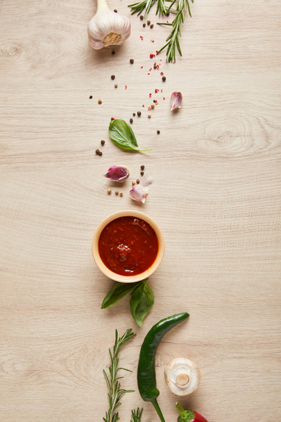 vista superior de delicioso molho de tomate na tigela perto de ervas e especiarias na mesa de madeira
 - Foto, Imagem