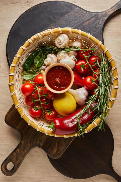 top view of delicious tomato sauce with fresh ripe vegetables in basket on wooden table with boards - Φωτογραφία, εικόνα