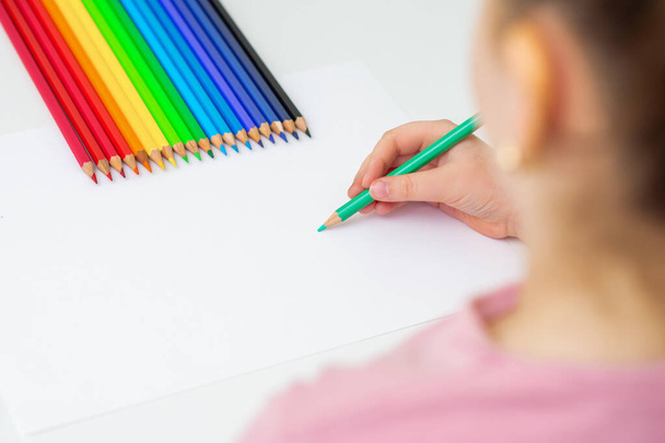 Roztomilé malé dítě kreslí barevnými tužkami na bílý papír. Kopírovat prostor pro text. Mockup. Selektivní zaměření. - Fotografie, Obrázek