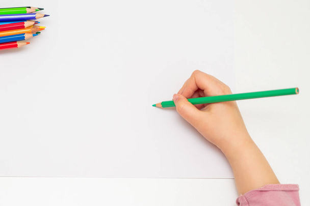 Vista superior del dibujo de la mano del niño en el papel blanco con lápices. Concepto de actividades escolares. Copia espacio para texto. Prepárate.
. - Foto, Imagen