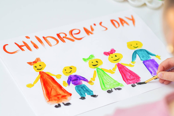 Meisje tekent de kinderen met woorden Kinderdag voor de feestdag Happy Children 's Day. - Foto, afbeelding