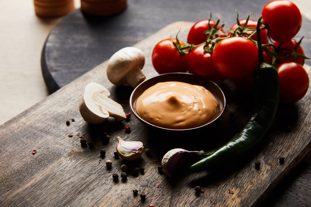 delicious sauce in bowl near mushrooms, tomatoes and spices on wooden board - Foto, afbeelding