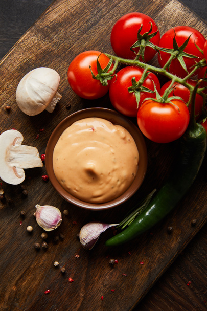 top view of delicious sauce in bowl near mushrooms, tomatoes and spices on wooden board - 写真・画像