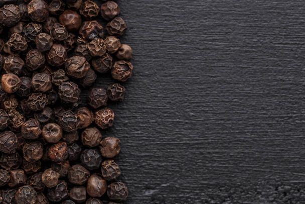 Peppercorn background. Dry black pepper seeds. Top view.On a black background. free space for your text. - Fotografie, Obrázek
