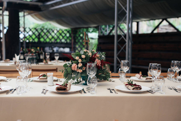 Kiev / Ucrânia - 02 / 09 / 2017 Decorações de casamento. Definição de mesa de casamento rústico. Placa, garfo, óculos, faca, toalha de mesa de tecido bege. Decoração com flores no meio da mesa
 - Foto, Imagem