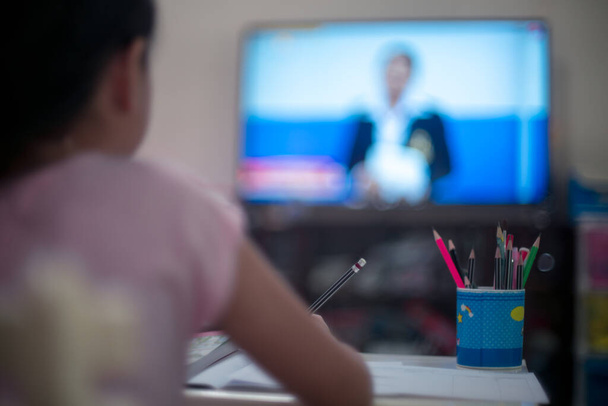 Μικρό παιδί κορίτσι μάθηση σε DLTV ή εξ αποστάσεως εκπαίδευση Τηλεόραση στο σπίτι, Κοινωνική απόσταση κατά τη διάρκεια της καραντίνας, Online έννοια της εκπαίδευσης - Φωτογραφία, εικόνα