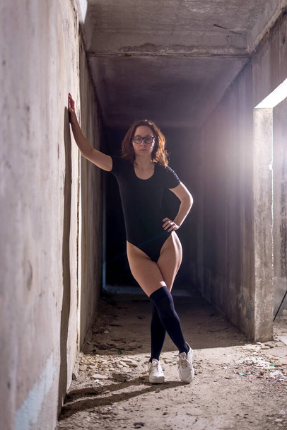 A young woman in stockings and body is standing near the wall. Slender woman. - Foto, imagen