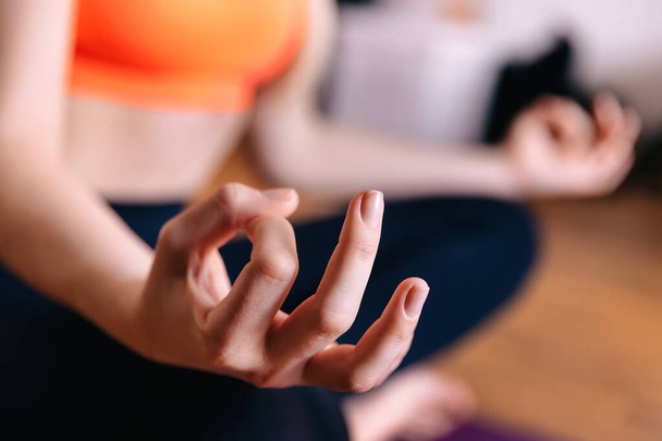 Close-up van handen meisje uit te werken op fitness mat, doen lotus yoga pose in het huis. Yoga-oefening, ontspannen en mediteren. - Foto, afbeelding