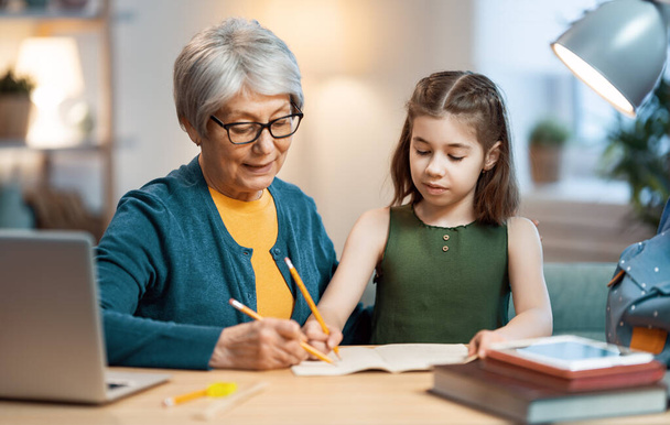 Back to school. Happy child is sitting at desk. Girl studying with grandma. - Foto, Imagem