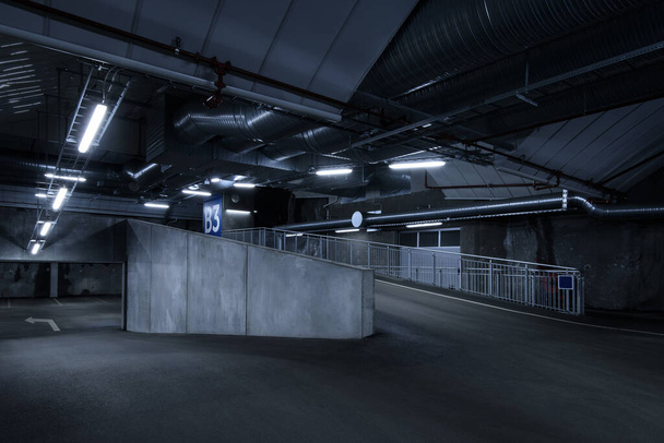 Sci fi looking dark and moody underground parking lot with fluorescent lights on.  A lot of concrete details. - Photo, Image