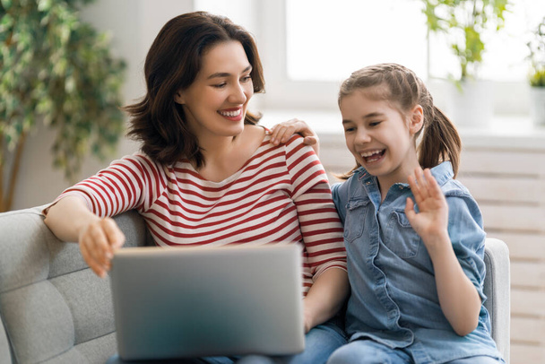 Happy loving family. Young mother and daughter girl using laptop. Funny mom and lovely child are having fun staying at home. - Foto, immagini