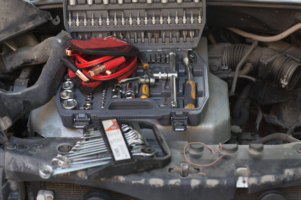 Auto, jossa on avoin huppu, sarja avaimia ja johtoja moottorin käynnistämiseksi - Valokuva, kuva