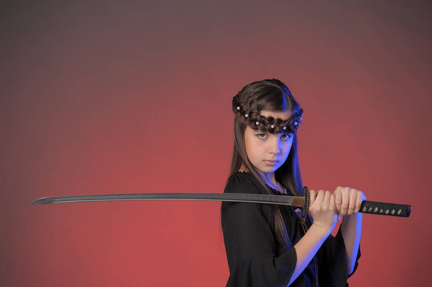 young warrior with a sword in her hands in the studio - Photo, image