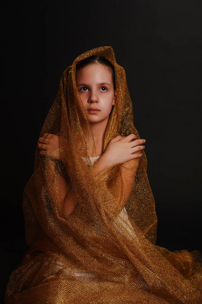 Young and beautiful girl praying on a dark background in the studio - 写真・画像