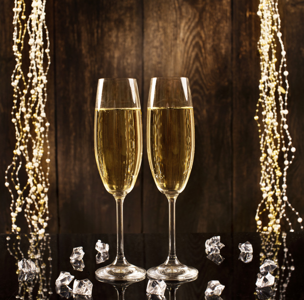 Glas champagne op een houten ondergrond met glanzende kristallen en bloemenslingers. Feestconcept met vrije ruimte voor tekst. Gelukkig Nieuwjaar! - Foto, afbeelding