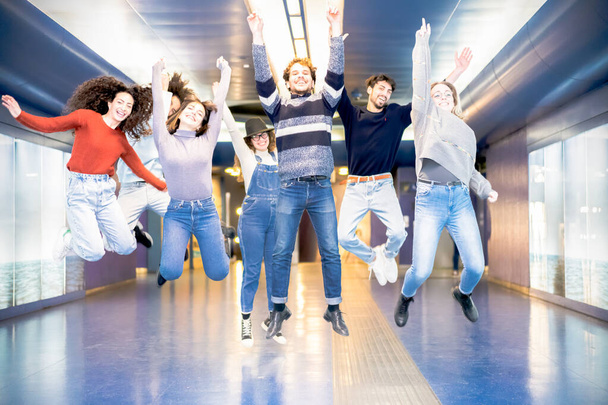 Щасливі тисячоліття друзі стрибають в приміщенні в метро. Молоді студенти розважаються разом, сміючись разом. Молодь, спосіб життя, команда, багаторасовий, концепція дружби - Зображення
 - Фото, зображення