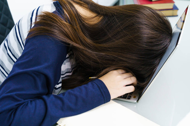 Молодая женщина длинные волосы устал от учебы в Интернете и заснуть на столе с ноутбуком
 - Фото, изображение
