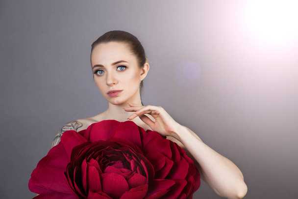 beautiful girl with healthy skin relaxes after a Spa treatment with a red flower - Photo, Image