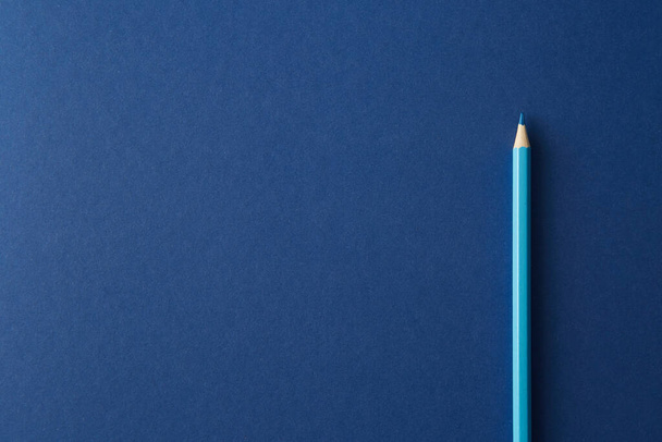 Blue colored pencil lying on a bright blue background, macro photography. - Foto, Imagen