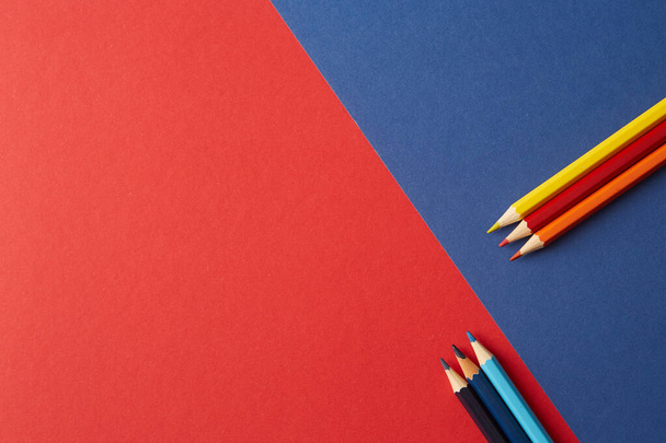 Lápices de colores de colores rojo-amarillo y azul están en el fondo de tonos rojos y azules
. - Foto, imagen