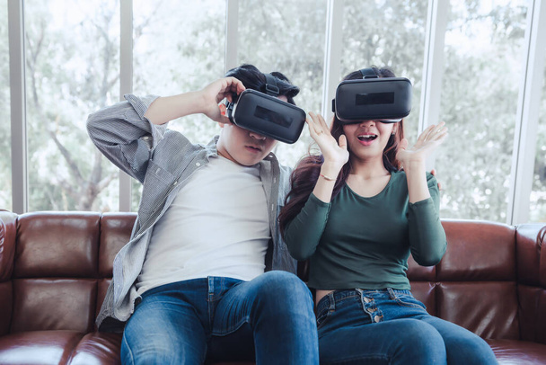 Młoda para bawiąca się ekscytująco oglądając razem film przez wirtualną rzeczywistość. Para Love korzystająca z elektronicznej gry wideo VR na kanapie. Rozrywka Innowacje / Koncepcja rzeczywistości wirtualnej - Zdjęcie, obraz