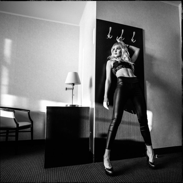 young beautiful blonde girl, alone, in black lingerie, in a hotel room - Zdjęcie, obraz