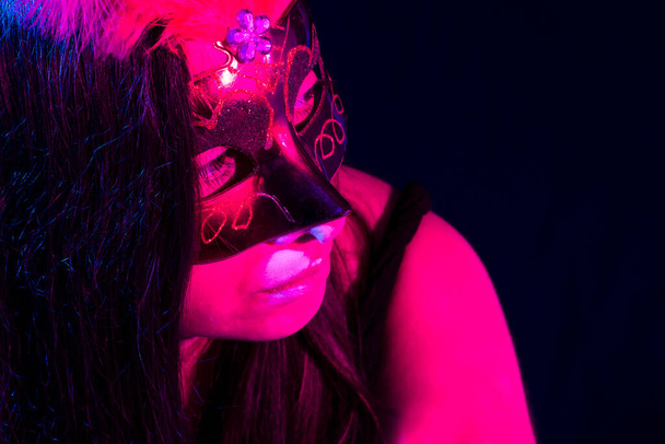 Žena v červené masce v baru s růžovým a modrým světlem.Nahoru pohled. - Fotografie, Obrázek