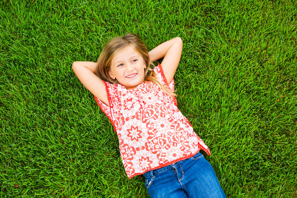 Smiling little girl lying on green grass - Zdjęcie, obraz