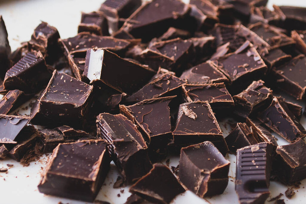 Una vista de cerca del chocolate negro cortado en cubos sobre una superficie blanca
 - Foto, imagen