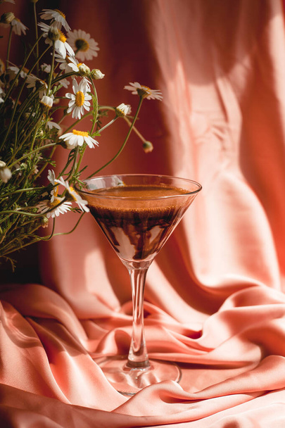 Glass with coffee on pink and a bouquet of daisies, silk fabric. Tasty drink.Blooming Wild Flower Matricaria Chamomilla Or Matricaria Recutita Or Chamomile. Commonly Known As Italian Camomilla, German - Photo, Image