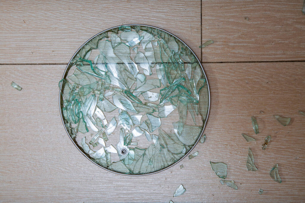 Egy törött üvegfedélről készült közeli kép fekszik egy cserepes karón. Üvegszilánkok ragyognak. lágy fókusz, felülnézet - Fotó, kép