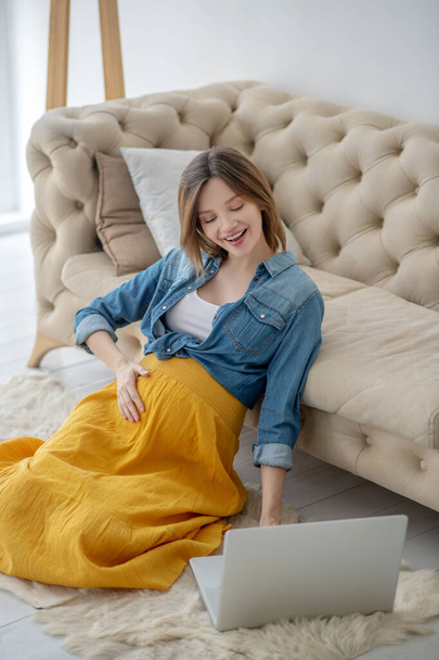 Young pregnant woman in a jeans jacket having a video chat - Fotoğraf, Görsel