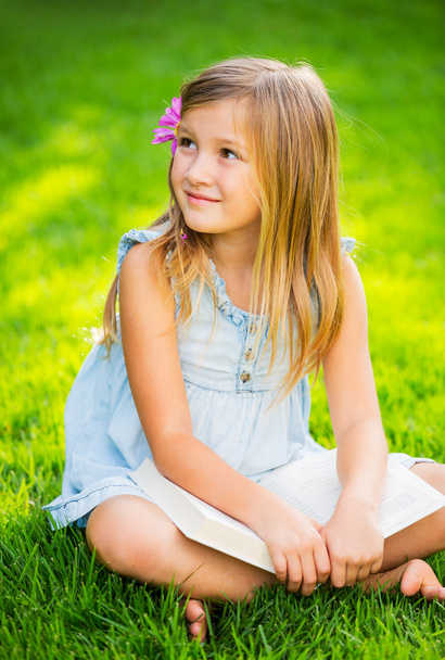 Маленькая девочка читает книгу снаружи
 - Фото, изображение