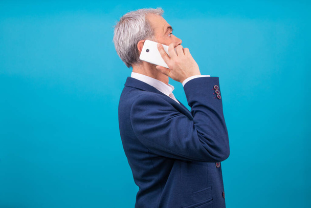 adult business man with mobile phone in profile isolated on color background - Photo, Image