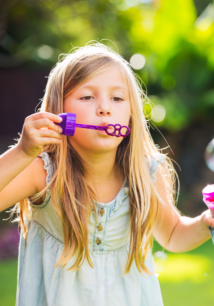 Cute little girl blowing soap bubbles - Фото, изображение