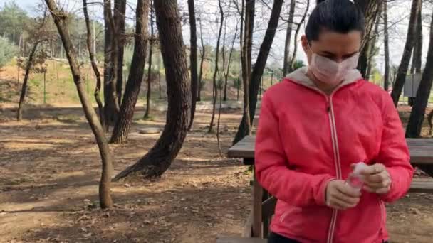 Frau mit Schutzmaske im Gesicht mit Händedesinfektionsmittel - Filmmaterial, Video