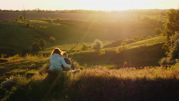 Máma se synem odpočívají společně na přírodě při západu slunce - Záběry, video