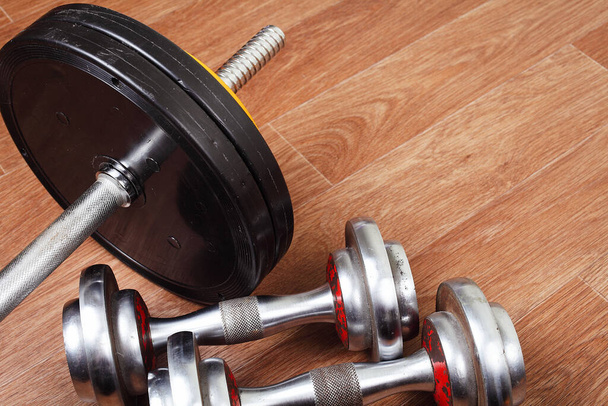 two dumbbells are lying on the floor next to the barbell in the gym. Place for text. - Photo, Image