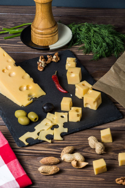 マスダマーチーズ。チーズプレートにチーズを切ったナッツハーブ古い黒い木製のテーブルの上にオリーブ。ワインとロマンス、チーズ料理のための食品。メニューデザイン。スコットランドのパターンを持つナプキンは - 写真・画像