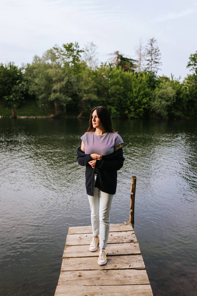 Giovane donna in piedi sul molo del fiume
  - Foto, immagini