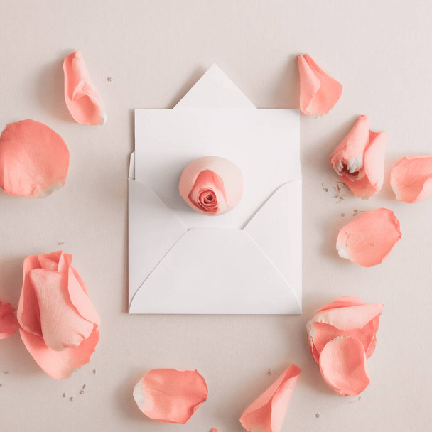 De envelop wenskaart, envelop met roos en bloemblaadjes. Bovenaanzicht, vlak. Kopieerruimte. - Foto, afbeelding