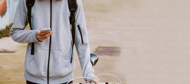 молодой подросток на улице с мобильным телефоном и велосипедом - Фото, изображение