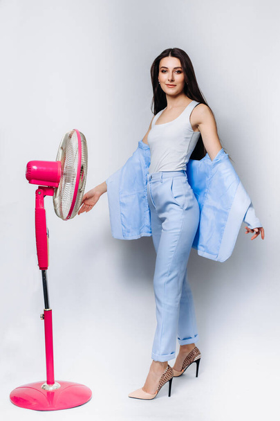 Businesswoman feels hot use a fan in the office struggle with the lack of air conditioning . Isolated on a white background. Wearing a blue business suit . Space for text. Isolated on background. - Foto, Bild