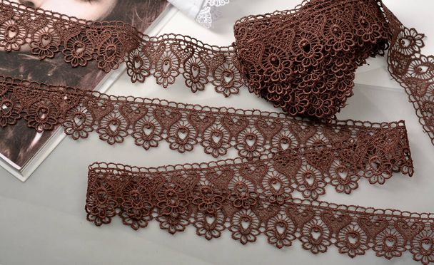 Tapes of brown gentle guipure, beauty lace fabric on light background. Elastic material. Using for Atelier and needlework store. - Photo, Image