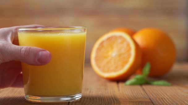 Hand picks up a glass of freshly squeezed orange juice - Séquence, vidéo
