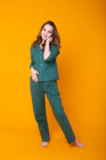 Smiling young girl in pajamas home wear posing while resting at home isolated on yellow background studio portrait. Relax good mood lifestyle concept. - Foto, Imagen
